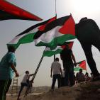 فلسطينيون يرفعون العلم الفلسطيني خلال تظاهرة ضد الاستيطان في قرية النبي صالح