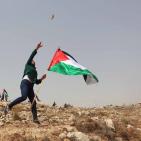 فلسطينيون يرفعون العلم الفلسطيني خلال تظاهرة ضد الاستيطان في قرية النبي صالح