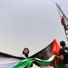 فلسطينيون يرفعون العلم الفلسطيني خلال تظاهرة ضد الاستيطان في قرية النبي صالح