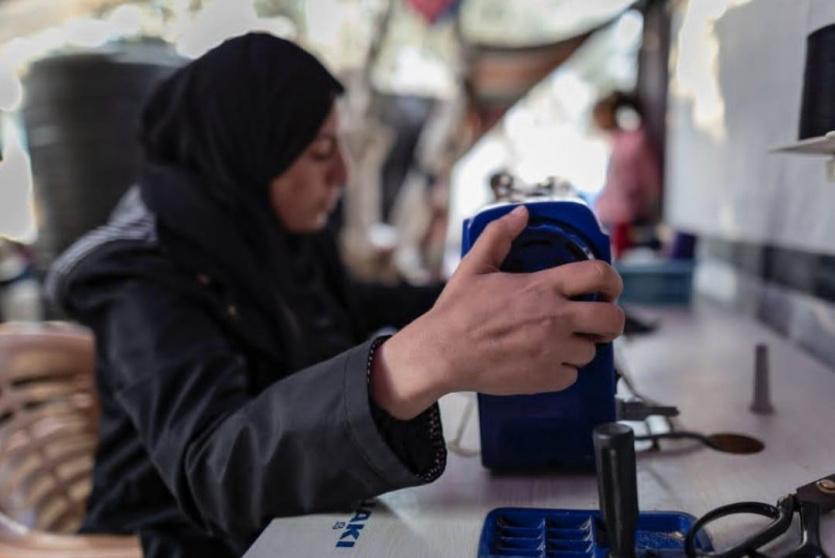 ولاء أبو ضباع تعمل على ماكينة الخياطة