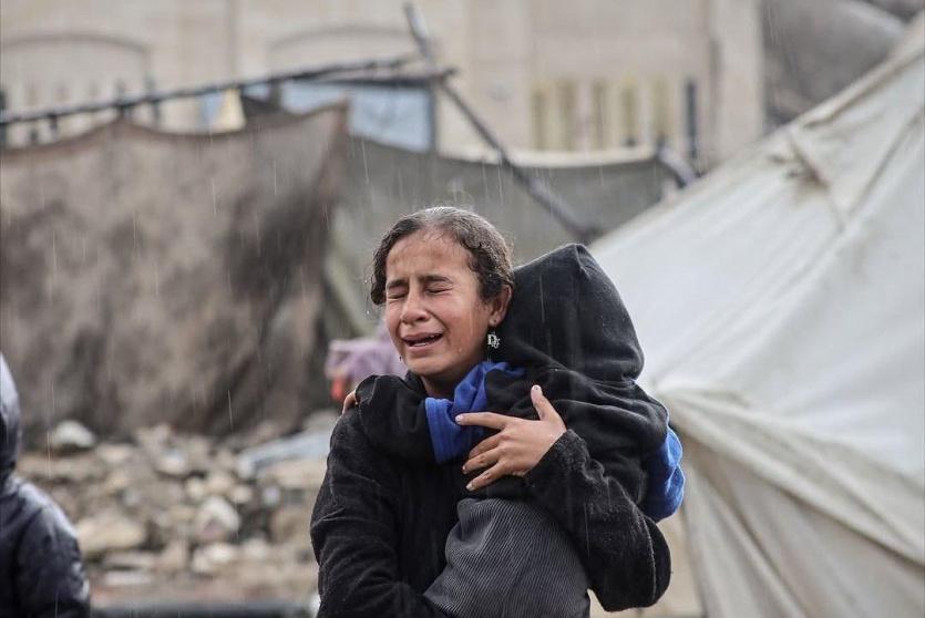 طفلة باكية تحمل طفلا وسط الأمطار الغزيرة 